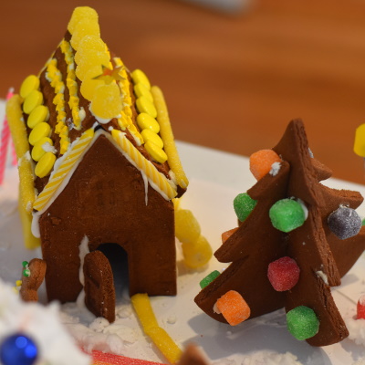 Gingerbread house decorated with yellow candies and and interlocking gingerbread Christmas tree.